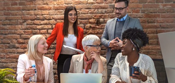 Shot of a group of businesspeople sitting together in a meeting. Group of people on a business meeting.  Aged businesswoman, teacher or business coach speaking to young people